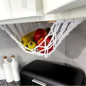Detail view of a white macramé fruit hammock hanging under a kitchen cabinet