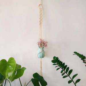 Detail of handmade cotton macrame plant hanger with wooden ring and mint green ceramic vase