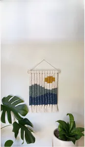 Detail of bohemian hand-woven tapestry featuring abstract mountain landscape and cotton fringe