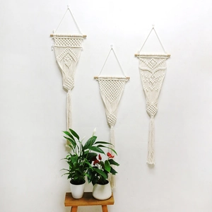 Detail of three handmade boho cotton rope wall hangings with fringe and wood rod