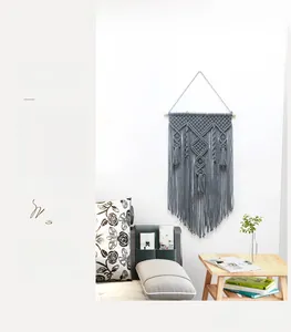 Macro view of Nordic style grey hand-woven cotton tapestry with bohemian fringe