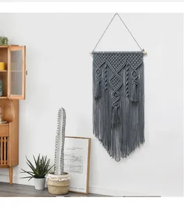 Detail of grey handmade bohemian macrame wall hanging with geometric weave and long tassels