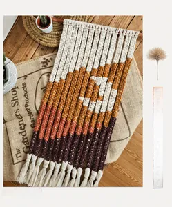 Detail of handmade macrame wall tapestry with yellow and purple fringe on wooden floor