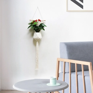Detail of hand-woven macrame plant hanger with cotton rope and wooden stick decor