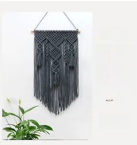 Detailed macro view of geometric diamond macrame pattern and fringe on gray wall hanging