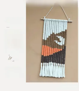 Detail of handmade woven wall tapestry featuring abstract mountain patterns and fringe
