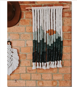 Detail of handmade bohemian woven wall hanging tapestry with colorful tassels on brick wall