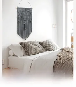 Detailed macro view of gray bohemian macramé wall hanging with tassels on wooden rod