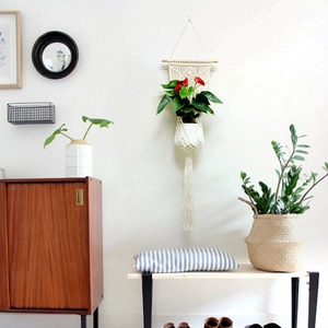 Detail of handmade woven cotton macrame plant hanger with wooden rod and long tassels