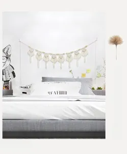 Dettaglio di decorazione murale in macramè con nappe di cotone e perline di legno