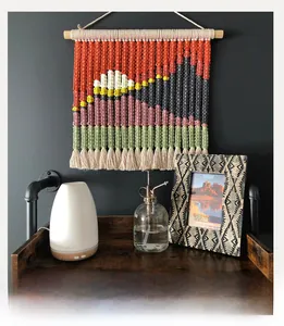 Detail of handmade macramé wall hanging featuring woven mountain scenery and sunset colors