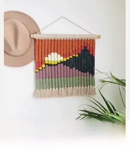 Detail of handmade woven macramé wall hanging featuring abstract sunset mountain landscape