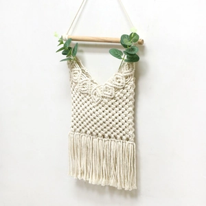 Detail of handwoven macrame wall hanging with wooden rod and fringe bohemian texture