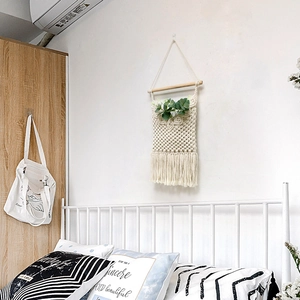 Detail of hand-woven bohemian wall tapestry storage bag with cotton fringe and wooden pole