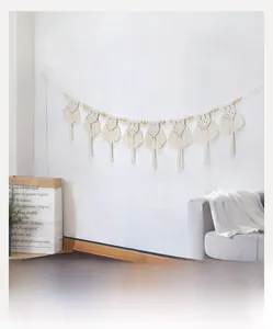 Dettaglio ravvicinato di decorazione murale in macramè fatta a mano con frange di cotone