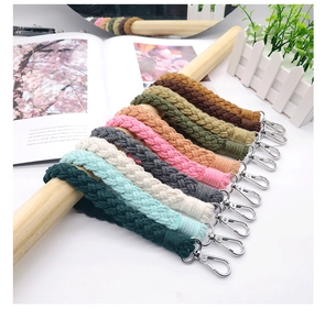 Detailed macro view of multi-color macrame cotton woven keychains hanging on wooden rod