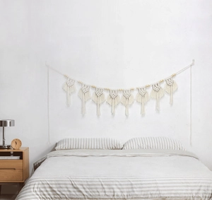 Dettaglio ravvicinato della decorazione da parete boho intrecciata a mano con nappe e perle