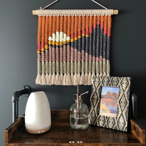Handmade woven macrame wall tapestry with colorful mountain landscape design and wooden rod