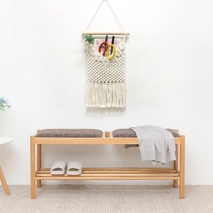 Minimalist solid wood shoe bench with grey cushions and bohemian woven wall hanging bag
