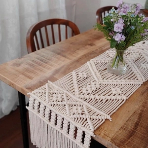 Detail of handcrafted macramé table runner with bohemian geometric patterns and tassels