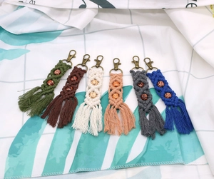 Detailed flat lay of handmade bohemian keychains featuring cotton fringe and wood beads