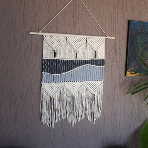 Detail of bohemian handmade woven wall hanging featuring cotton rope tassels and wooden beads