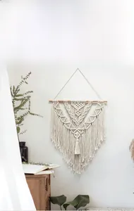 Detail of bohemian handmade woven wall tapestry with cotton tassels and wood rod