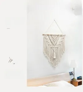 Close-up of bohemian hand-woven cotton macrame wall hanging with wooden rod and tassels
