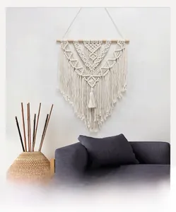 Detail of bohemian handmade woven tapestry with geometric cotton rope patterns and wood pole