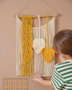 Detailansicht der handgewebten Wanddekoration im Boho-Stil mit gelben Blattfransen