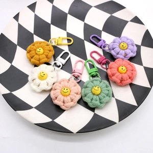 Close-up of colorful knitted flower keychains with smiley faces on checkered tray