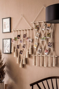 Détail du mur de photos en macramé bohème avec pompons en coton et pinces en bois