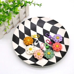 Close-up of seven colorful woven cotton flower keychains with yellow smiley face centers