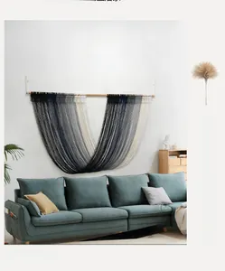 Macro shot of hand-woven gradient fringe tapestry with wooden rod on modern sofa wall