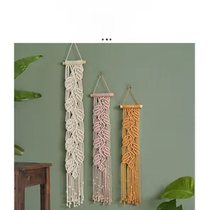Détail de décoration murale en macramé fait main avec feuilles en coton et bois naturel