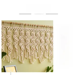 Détail d'une décoration murale bohème en macramé tissé main avec motifs feuilles et franges