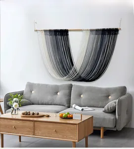 Detail of bohemian macramé wall hanging with gradient gray cotton tassels on a wooden pole