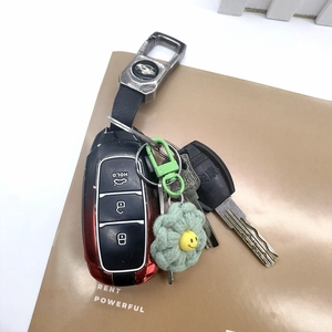 Detail of handmade green crochet flower keychain with smiley face bead on Cadillac keys
