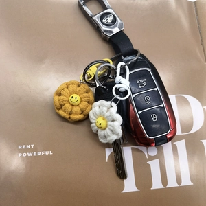 Handmade crochet flower keychains with smiley faces and metal rings on a magazine