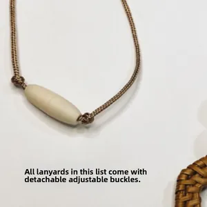 Detail of adjustable beige buckle on brown braided lanyard for ID cards and keys