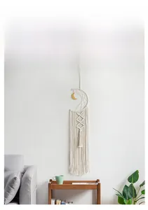 Handwoven moon-shaped macramé wall hanging with cotton tassels in a cozy living room scene