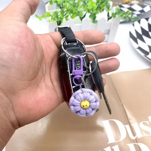 Detailed close-up of a purple woven flower keychain with a yellow smiley face button