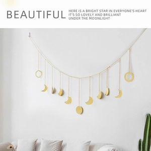 Detail of brass moon phase wall hanging with metallic chains against a white wall