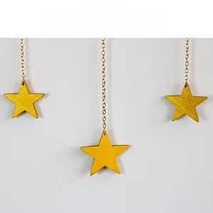 Close-up of golden metal star pendants with a fine sand texture and elegant hanging chains