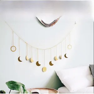 Detail of gold metal moon phase wall hanging with moon pendants for bedroom decor