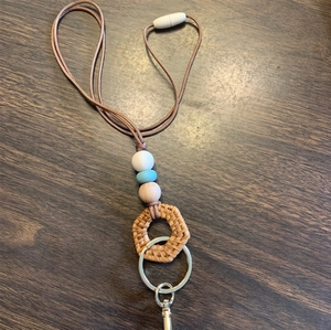 Detail of handmade beaded lanyard with braided cord, beads, and lobster clasp on dark wood