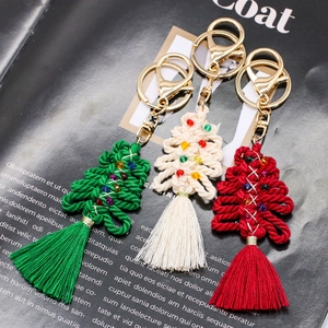 Handmade macrame Christmas tree keychains with colorful beads and tassels on a magazine