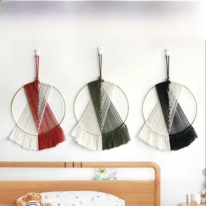 Detail of bohemian handmade woven wall hanging featuring cotton tassels and wooden beads
