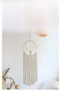 Detail of handcrafted bohemian dream catcher with cotton tassels and gold metal rings