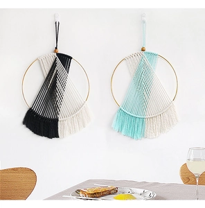 Detail of geometric woven wall hanging featuring cotton tassels and metal rings decoration